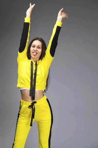 Portrait of a young beautiful brunette woman in yellow tracksuit — Stock Photo, Image