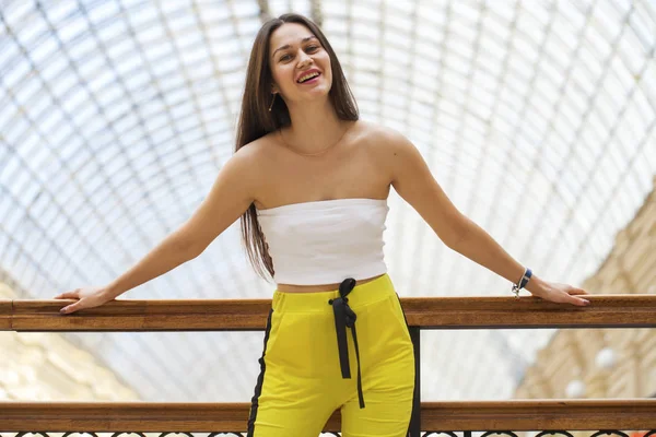 Jong mooi brunette vrouw in een wit top en geel sport — Stockfoto