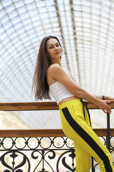 Young beautiful brunette woman in a white top and yellow sports — 스톡 사진