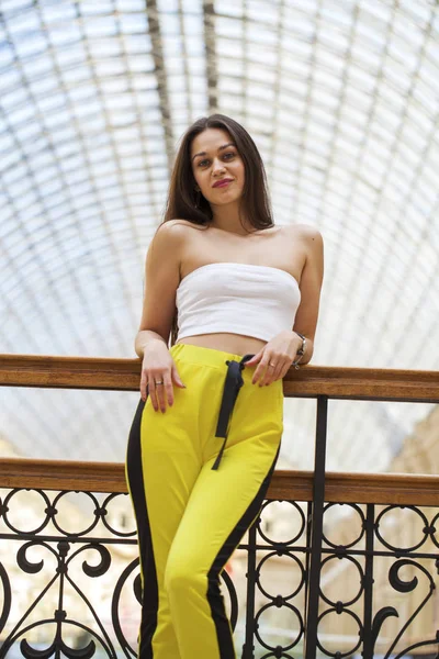Young beautiful brunette woman in a white top and yellow sports — 스톡 사진