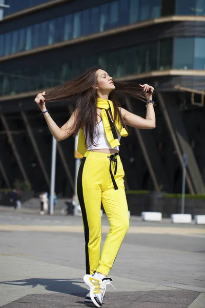 一个年轻的美丽的黑发女人在黄色运动服的肖像 — 图库照片