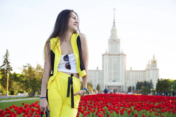 Junge brünette Frauen auf dem Hintergrund einer Lichtung von Tulpen fließen — Stockfoto