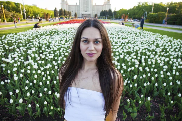 Mulheres morenas jovens no fundo de uma clareira de fluxo de tulipas — Fotografia de Stock