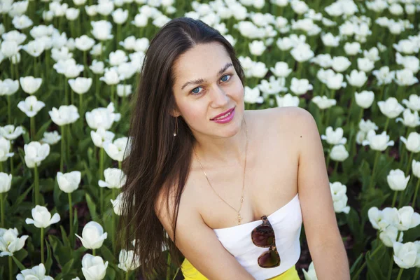 Mujeres morenas jóvenes en el fondo de un claro de tulipanes fluyen — Foto de Stock