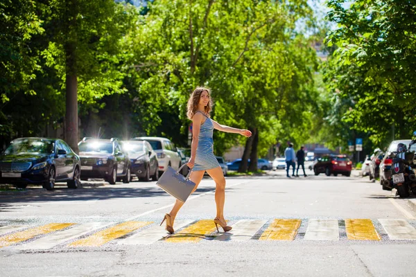 Mooie jongedame in een blauwe korte jurk lopen op de weg — Stockfoto