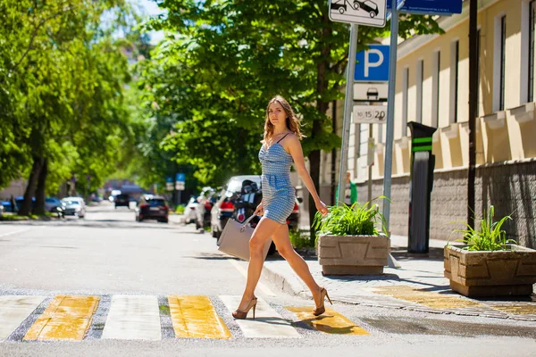 Jovem mulher bonita em um vestido curto azul andando na estrada — Fotografia de Stock