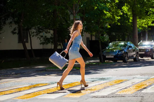 Молодая красивая женщина в синем коротком платье, идущая по дороге — стоковое фото