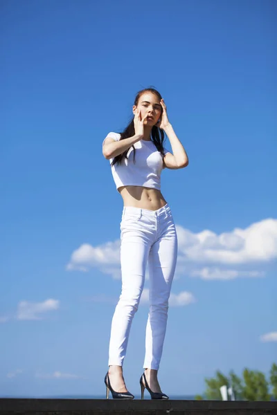 Schöne brünette Frau posiert vor blauem Himmel strahlend sonnig wir — Stockfoto