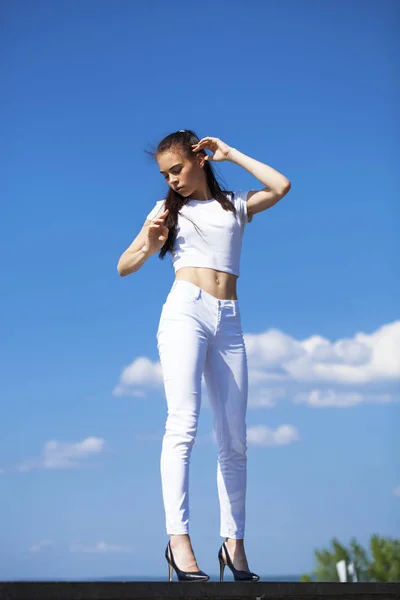 Hermosa mujer morena posando contra el cielo azul brillante soleado nosotros —  Fotos de Stock