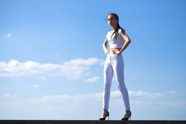 Hermosa mujer morena posando contra el cielo azul brillante soleado nosotros — Foto de Stock