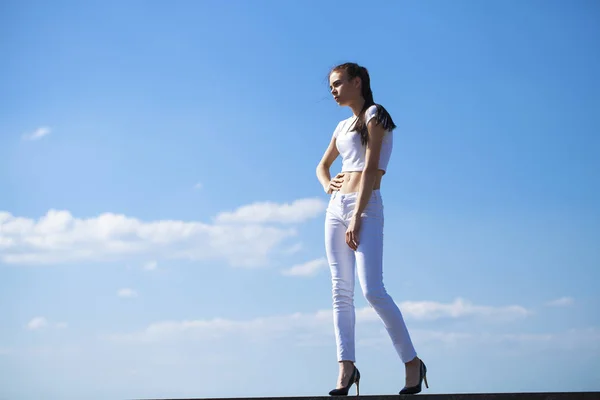 Beautiful brunette woman posing against blue sky bright sunny we — Stock Photo, Image