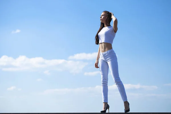 Bela morena mulher posando contra azul céu brilhante ensolarado nós — Fotografia de Stock