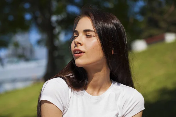 Mooie brunette vrouw poseren tegen zomerpark, heldere Sunn — Stockfoto