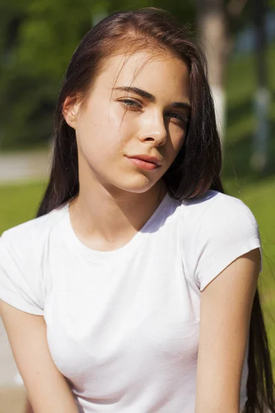 Hermosa mujer morena posando contra el parque de verano, sol brillante —  Fotos de Stock