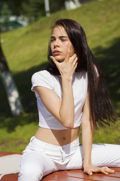 Mooie brunette vrouw poseren tegen zomerpark, heldere Sunn — Stockfoto