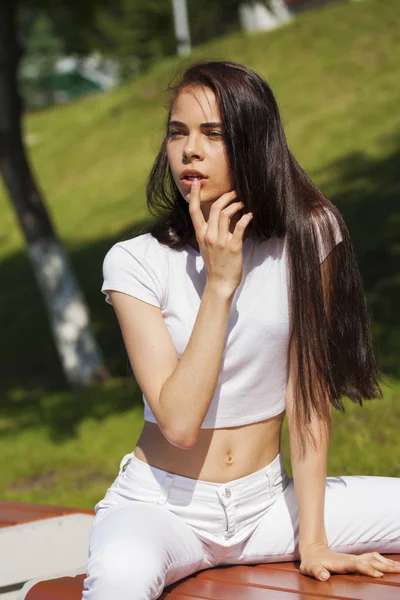 Mooie brunette vrouw poseren tegen zomerpark, heldere Sunn — Stockfoto