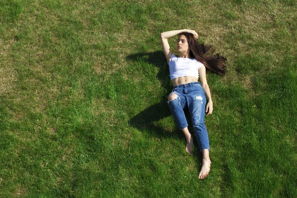 Retrato de una joven hermosa niña descansando en el césped en el pa —  Fotos de Stock