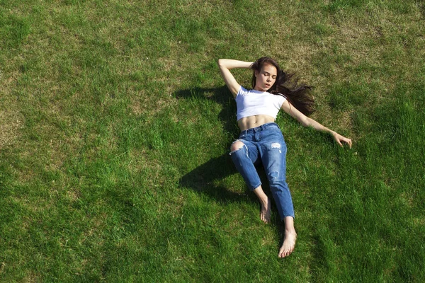 Retrato de una joven hermosa niña descansando en el césped en el pa — Foto de Stock