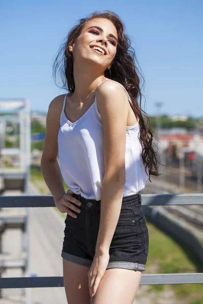 Улыбающаяся модель брюнетки в белой летней блузке, летняя улица — стоковое фото