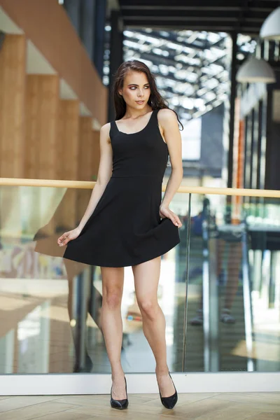 Full body portrait of a happy young brunette woman in black dres