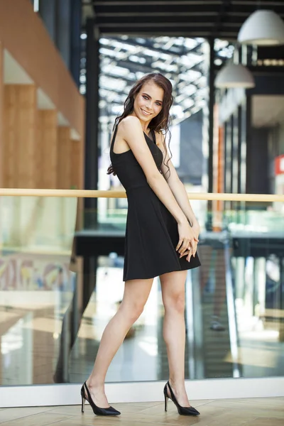 Full body portrait of a happy young brunette woman in black dres