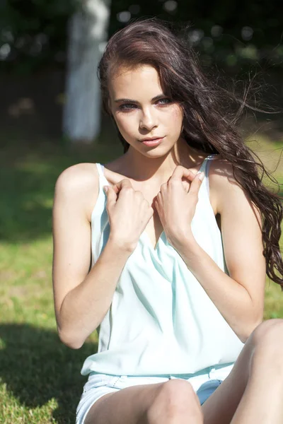 Jonge brunette vrouw in een turquoise blouse poseren zittend op een g — Stockfoto