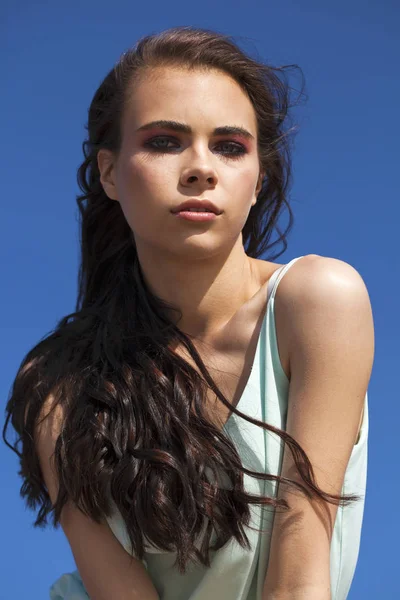 Young beautiful woman in a turquoise blouse posing against the b — Stock Photo, Image