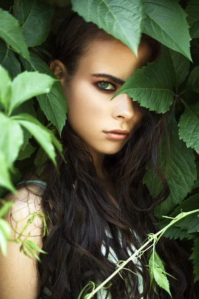 Portret van een jong mooi meisje in groene klimop gebladerte — Stockfoto
