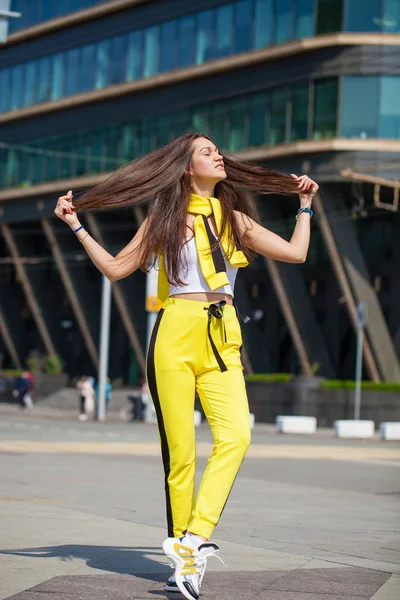 一个年轻的美丽的黑发女人在黄色运动服的肖像 — 图库照片