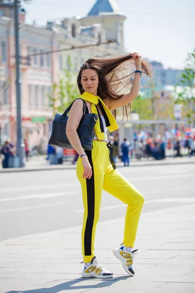 Porträtt av en ung vacker brunett kvinna i gul träningsoverall — Stockfoto