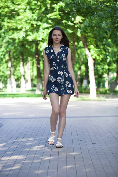 Joven hermosa mujer en un vestido corto azul caminando por el camino — Foto de Stock