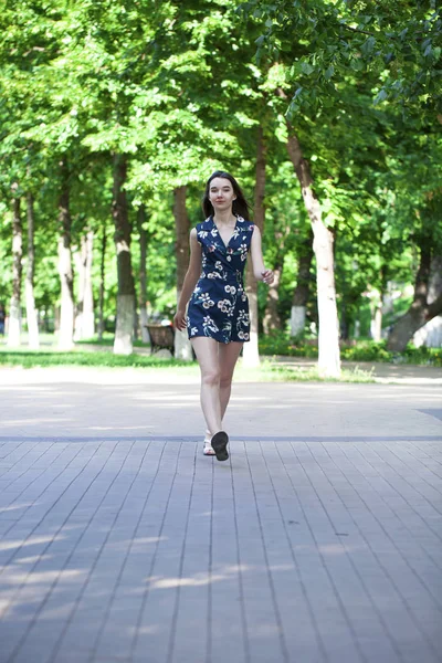 Jovem mulher bonita em um vestido curto azul andando na estrada — Fotografia de Stock