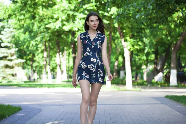 Jovem mulher bonita em um vestido curto azul andando na estrada — Fotografia de Stock