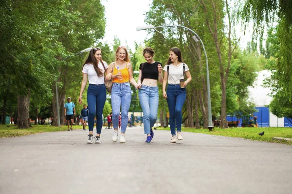 Счастливые женщины в синих джинсах гуляют в летнем парке — стоковое фото