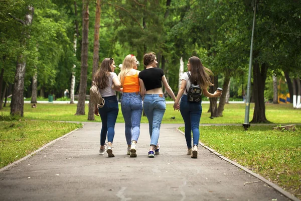 Счастливые женщины в синих джинсах гуляют в летнем парке — стоковое фото