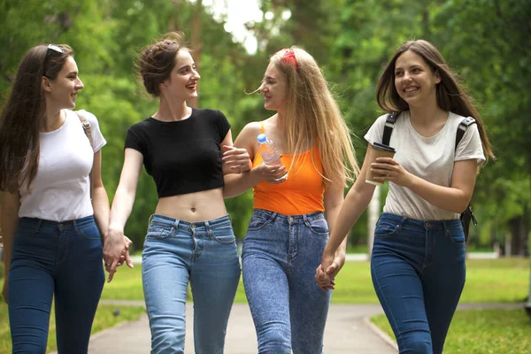 Quatro alunas felizes andando no parque de verão — Fotografia de Stock