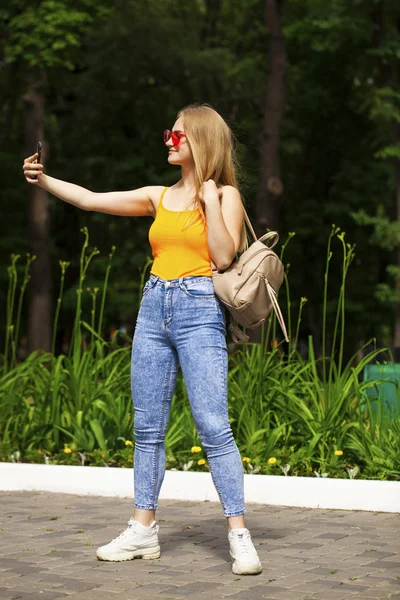 Mladá krásná žena s mobilem procházky v letním parku — Stock fotografie