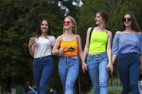 Quatro alunas felizes andando no parque de verão — Fotografia de Stock