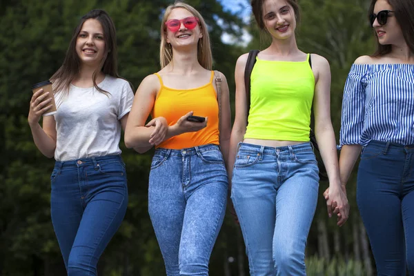Vier gelukkige schoolmeisjes wandelen in het zomerpark — Stockfoto