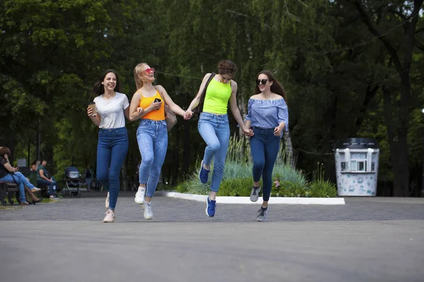 穿着蓝色牛仔裤的快乐女性在夏季公园散步 — 图库照片