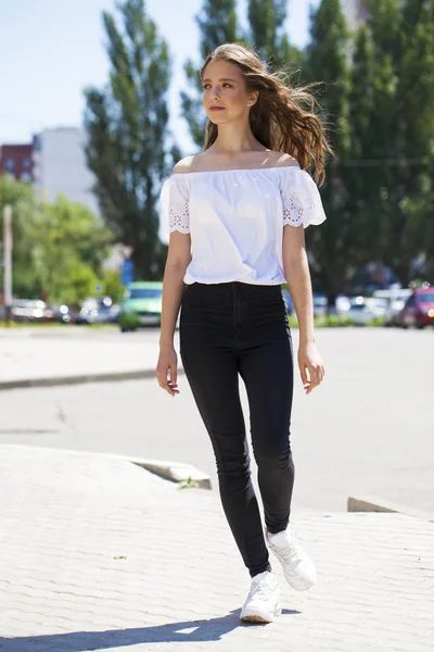 Joven hermosa morena mujer en jeans y blusa blanca caminando —  Fotos de Stock