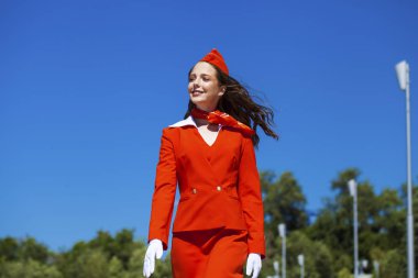 Beautiful stewardess dressed in official red uniform gainst a bl clipart