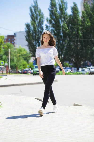 Jovem bela mulher morena em jeans e blusa branca andando — Fotografia de Stock