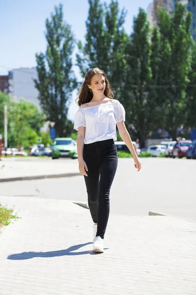 Joven hermosa morena mujer en jeans y blusa blanca caminando —  Fotos de Stock