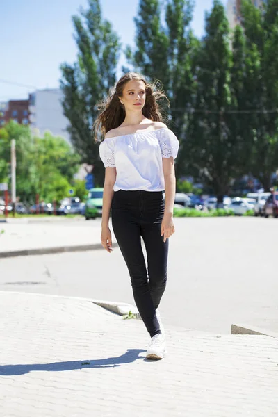 Joven hermosa morena mujer en jeans y blusa blanca caminando —  Fotos de Stock