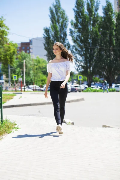 Jovem bela mulher morena em jeans e blusa branca andando — Fotografia de Stock