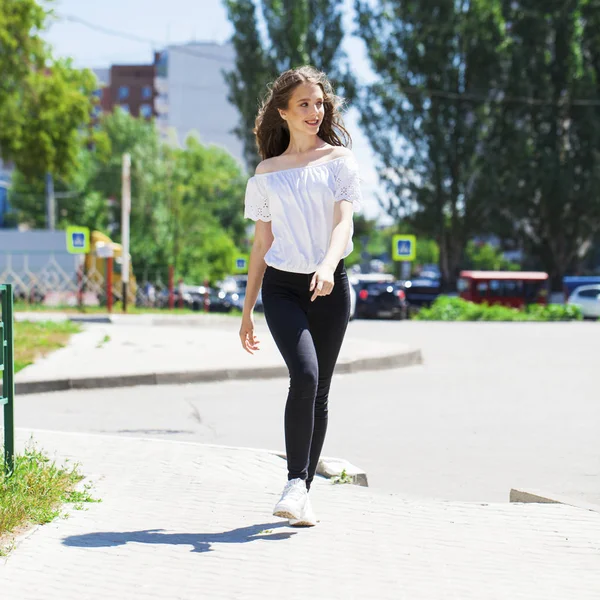 Kot pantolon ve beyaz bluz yürüyüş genç güzel esmer kadın — Stok fotoğraf