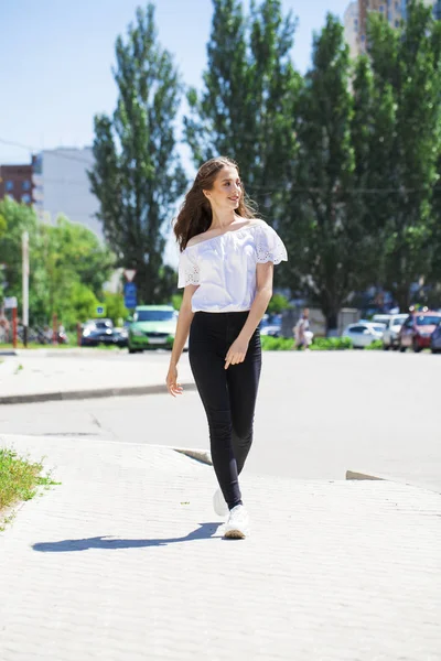 युवा सुंदर श्यामला महिला में जीन्स आणि पांढरा ब्लाउज चालणे — स्टॉक फोटो, इमेज