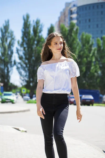 Jeune belle femme brune en jeans et chemisier blanc marche — Photo