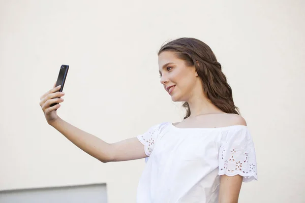 Hübsche junge brünette Frau macht Selfie auf dem Smartphone — Stockfoto